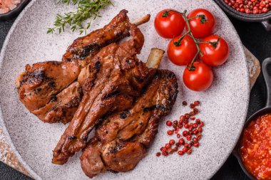 Izgarada pişmiş biftek, tuz, baharat ve otlarla birlikte koyu beton bir arka planda.