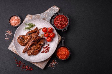 Izgarada pişmiş biftek, tuz, baharat ve otlarla birlikte koyu beton bir arka planda.