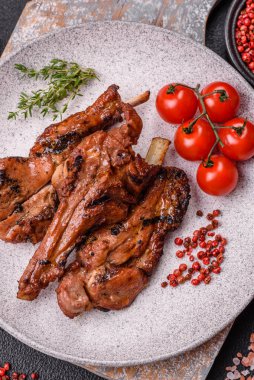 Izgarada pişmiş biftek, tuz, baharat ve otlarla birlikte koyu beton bir arka planda.