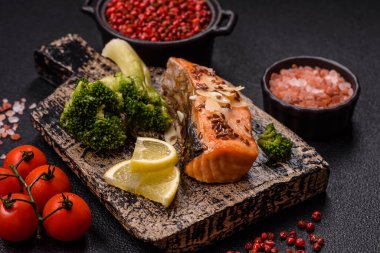 Tuz ve baharatlı ızgara somon, brokoli, domates, koyu beton arka planda pirinç.