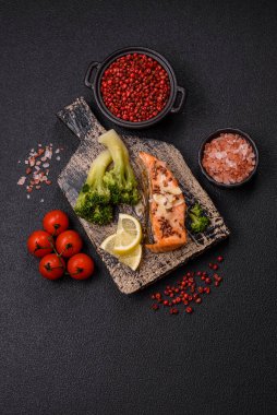 Tuz ve baharatlı ızgara somon, brokoli, domates, koyu beton arka planda pirinç.