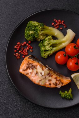 Tuz ve baharatlı ızgara somon, brokoli, domates, koyu beton arka planda pirinç.