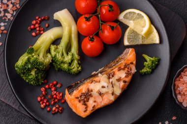 Tuz ve baharatlı ızgara somon, brokoli, domates, koyu beton arka planda pirinç.