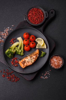 Tuz ve baharatlı ızgara somon, brokoli, domates, koyu beton arka planda pirinç.