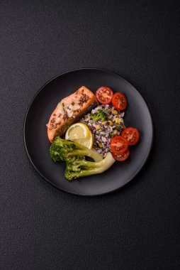 Tuz ve baharatlı ızgara somon, brokoli, domates, koyu beton arka planda pirinç.