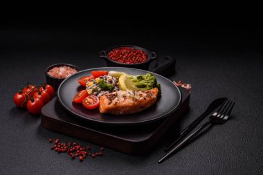 Tuz ve baharatlı ızgara somon, brokoli, domates, koyu beton arka planda pirinç.