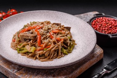 Karabuğday eriştesi, sebzeli, tuzlu ve baharatlı, koyu beton arka planda.