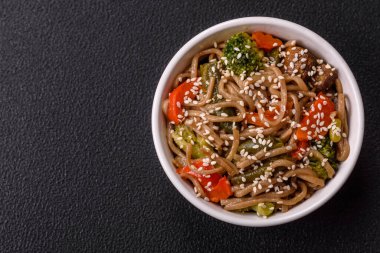 Karabuğday eriştesi, sebzeli, tuzlu ve baharatlı, koyu beton arka planda.