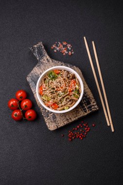 Karabuğday eriştesi, sebzeli, tuzlu ve baharatlı, koyu beton arka planda.