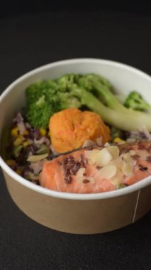 Tuz ve baharatlı ızgara somon, brokoli, domates, koyu beton arka planda pirinç.