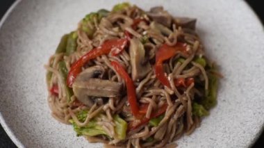 Karabuğday eriştesi, sebzeli, tuzlu ve baharatlı, koyu beton arka planda.