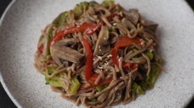 Karabuğday eriştesi, sebzeli, tuzlu ve baharatlı, koyu beton arka planda.