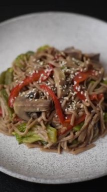 Karabuğday eriştesi, sebzeli, tuzlu ve baharatlı, koyu beton arka planda.