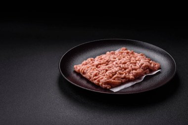 Koyu beton arka planda tuzlu, baharatlı ve otlu çiğ tavuk.