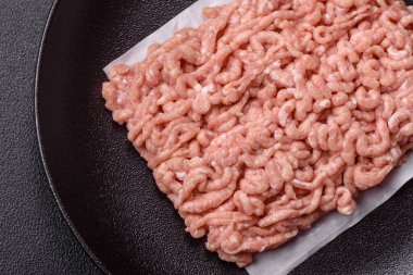 Koyu beton arka planda tuzlu, baharatlı ve otlu çiğ tavuk.