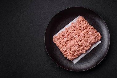 Koyu beton arka planda tuzlu, baharatlı ve otlu çiğ tavuk.