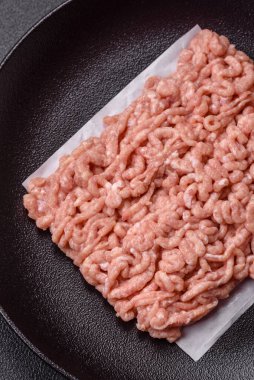 Koyu beton arka planda tuzlu, baharatlı ve otlu çiğ tavuk.