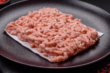 Koyu beton arka planda tuzlu, baharatlı ve otlu çiğ tavuk.