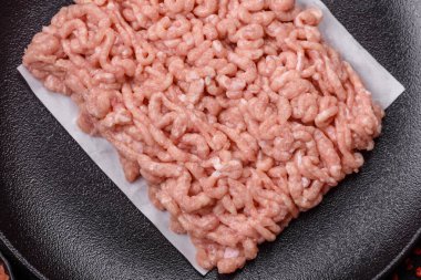 Koyu beton arka planda tuzlu, baharatlı ve otlu çiğ tavuk.