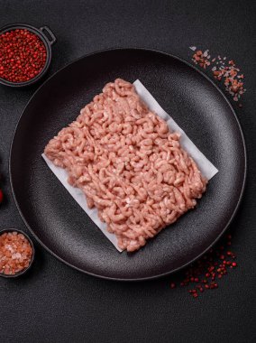 Koyu beton arka planda tuzlu, baharatlı ve otlu çiğ tavuk.