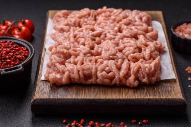 Koyu beton arka planda tuzlu, baharatlı ve otlu çiğ tavuk.