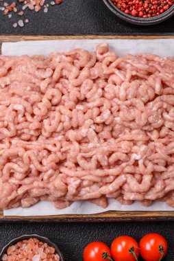 Koyu beton arka planda tuzlu, baharatlı ve otlu çiğ tavuk.