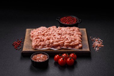 Koyu beton arka planda tuzlu, baharatlı ve otlu çiğ tavuk.