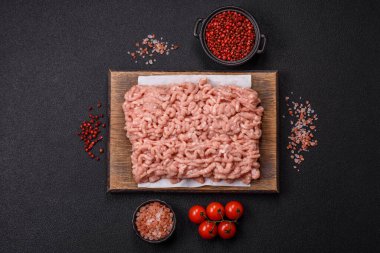 Koyu beton arka planda tuzlu, baharatlı ve otlu çiğ tavuk.