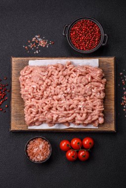 Koyu beton arka planda tuzlu, baharatlı ve otlu çiğ tavuk.