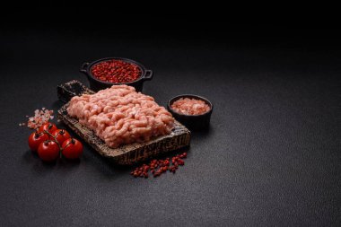 Koyu beton arka planda tuzlu, baharatlı ve otlu çiğ tavuk.