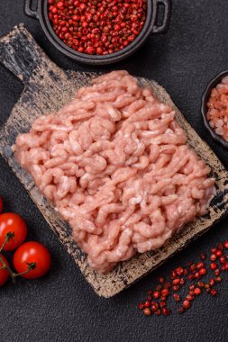 Koyu beton arka planda tuzlu, baharatlı ve otlu çiğ tavuk.