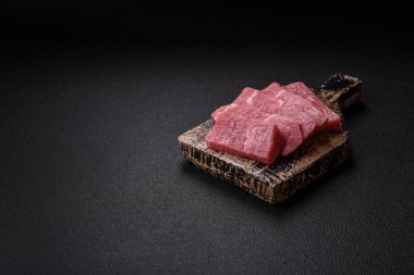 Koyu beton zeminde tuz, baharat ve otlarla dilimlenmiş sulu sığır eti.