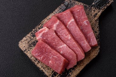 Koyu beton zeminde tuz, baharat ve otlarla dilimlenmiş sulu sığır eti.