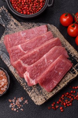 Koyu beton zeminde tuz, baharat ve otlarla dilimlenmiş sulu sığır eti.