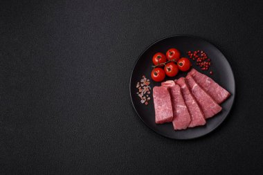 Koyu beton zeminde tuz, baharat ve otlarla dilimlenmiş sulu sığır eti.