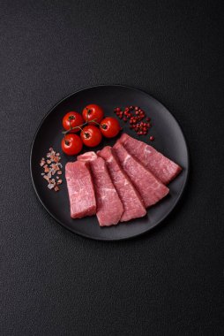 Koyu beton zeminde tuz, baharat ve otlarla dilimlenmiş sulu sığır eti.