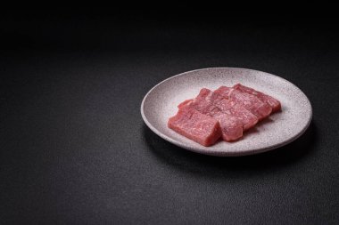 Koyu beton zeminde tuz, baharat ve otlarla dilimlenmiş sulu sığır eti.