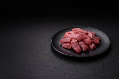 Koyu beton zeminde tuz, baharat ve otlarla dilimlenmiş sulu sığır eti.