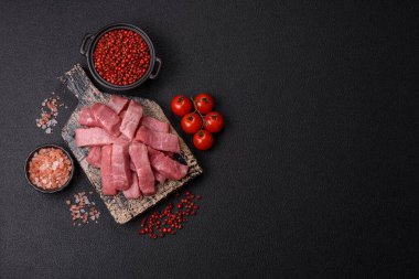 Koyu beton zeminde tuz, baharat ve otlarla dilimlenmiş sulu sığır eti.