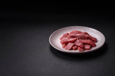 Koyu beton zeminde tuz, baharat ve otlarla dilimlenmiş sulu sığır eti.