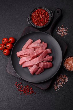 Koyu beton zeminde tuz, baharat ve otlarla dilimlenmiş sulu sığır eti.