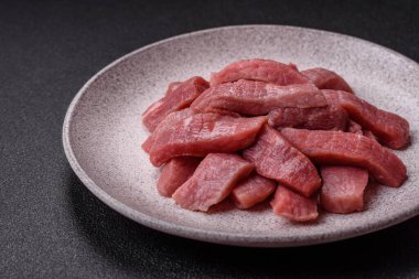 Koyu beton zeminde tuz, baharat ve otlarla dilimlenmiş sulu sığır eti.