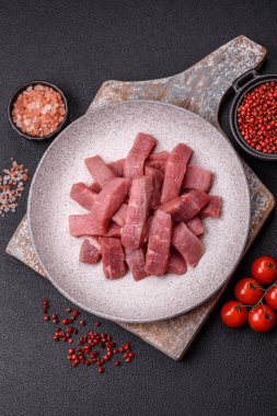 Koyu beton zeminde tuz, baharat ve otlarla dilimlenmiş sulu sığır eti.