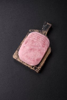 Jambon, tuzlu konserve jambon, baharat ve otlar koyu beton arka planda dilimler halinde kesilmiş.