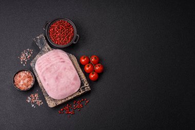 Jambon, tuzlu konserve jambon, baharat ve otlar koyu beton arka planda dilimler halinde kesilmiş.