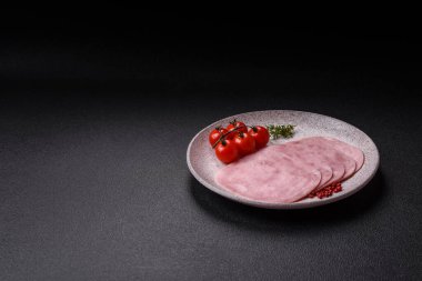 Jambon, tuzlu konserve jambon, baharat ve otlar koyu beton arka planda dilimler halinde kesilmiş.