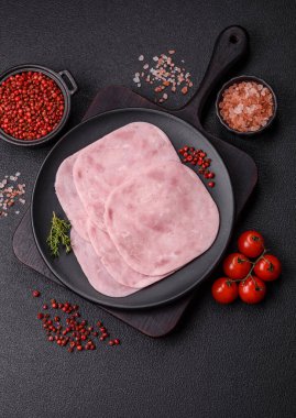 Jambon, tuzlu konserve jambon, baharat ve otlar koyu beton arka planda dilimler halinde kesilmiş.