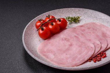 Jambon, tuzlu konserve jambon, baharat ve otlar koyu beton arka planda dilimler halinde kesilmiş.
