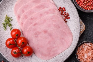 Jambon, tuzlu konserve jambon, baharat ve otlar koyu beton arka planda dilimler halinde kesilmiş.