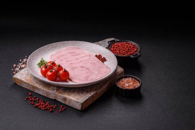 Jambon, tuzlu konserve jambon, baharat ve otlar koyu beton arka planda dilimler halinde kesilmiş.